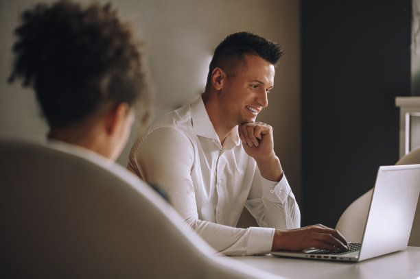 男人侧身对着摄像机看笔记本电脑和女人图片下载