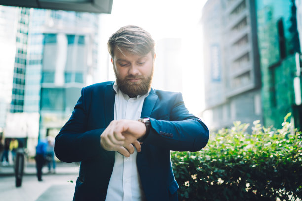 西装革履的务实商人在市中心看手表图片下载