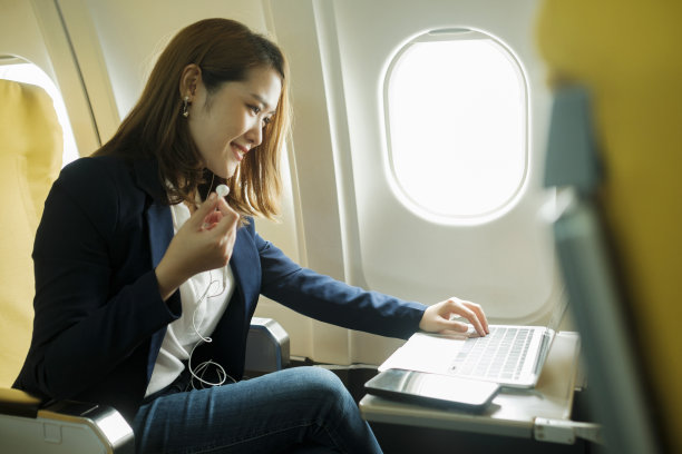 商务女性坐在飞机上用笔记本电脑工作。图片下载
