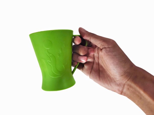 手拿一个白色背景的绿色塑料杯图片下载