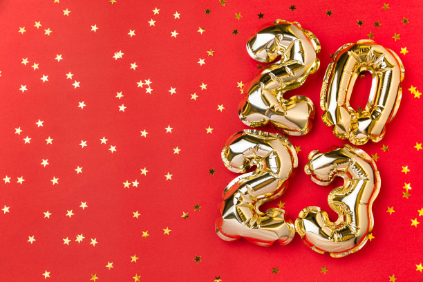 2023年新年气球庆祝卡。金箔氦气球编号2023和金色五彩纸屑星星孤立在红色背景。平铺，圣诞快乐，节日快乐。图片下载