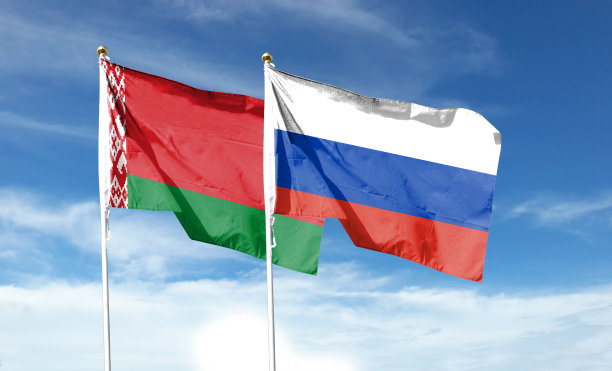俄罗斯国旗和白俄罗斯国旗在多云的天空。在天空中舞动图片下载