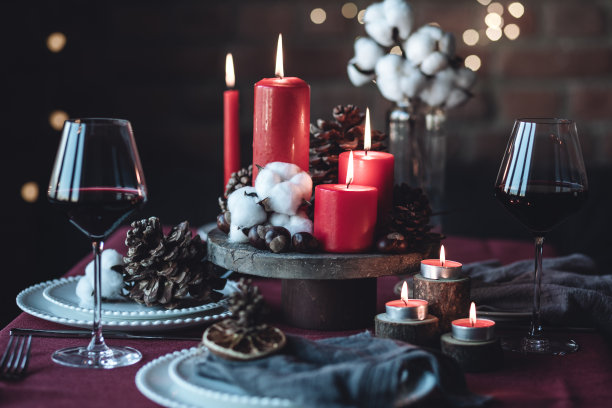 圣诞或新年家庭晚餐的乡村餐桌装饰。中心装饰有红蜡烛，干橙，圆锥体，肉桂，八角。零废物环保之家。舒适的氛围，黑色的背景。近距离图片下载