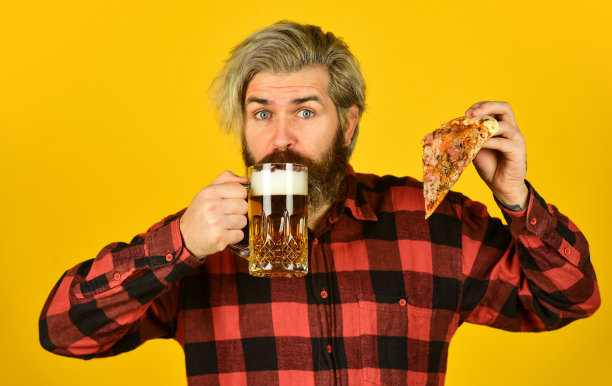 意大利菜。意大利在这里。有人在酒吧喝啤酒吃披萨。欢呼。一杯啤酒和披萨。在电视上看足球比赛。快餐。快乐的大胡子，啤酒和披萨图片下载