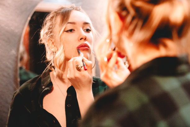 年轻女子用唇笔画轮廓，涂口红，在家里化妆，准备出门图片下载