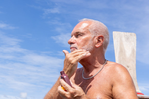 船上的老人在脸上涂防晒霜图片下载