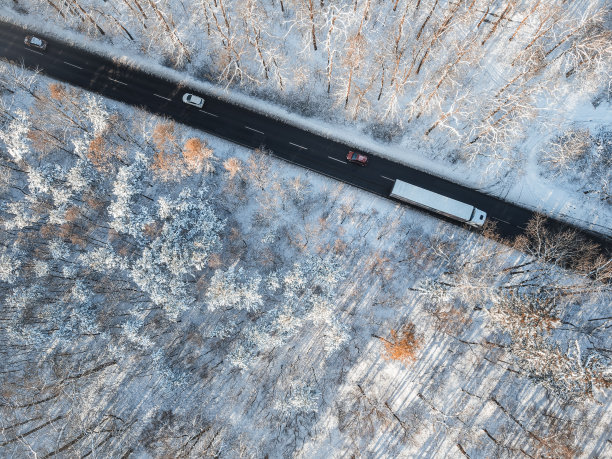 高空俯视的道路与汽车通过雪林。图片下载