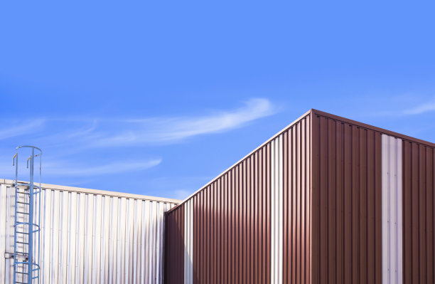 两座仓库建筑的波纹钢墙和金属楼梯，背景是蓝天图片下载