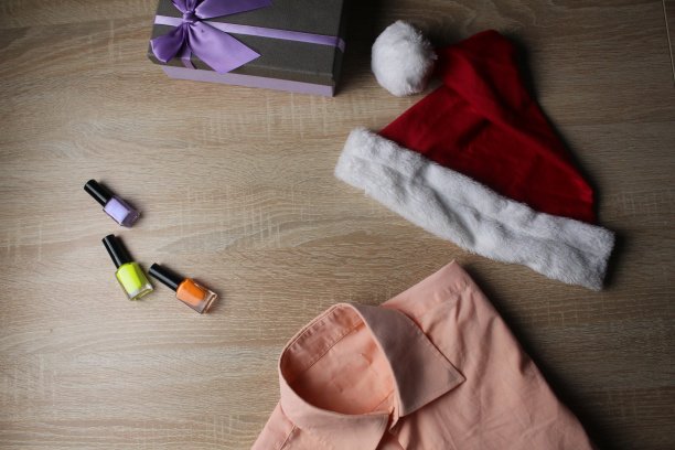 圣诞节和新年的衣服。为假期做准备。衬衫，帽子，雪橇礼物和指甲油在木制背景。圣诞节图片图片下载