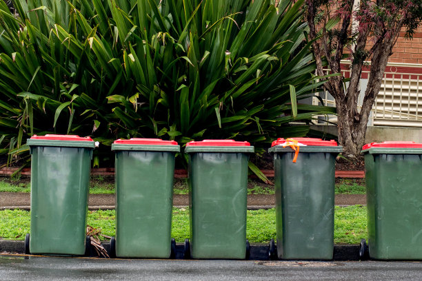 澳大利亚有红色盖子的垃圾筒在居民楼附近的街道上排成一排，供市政垃圾收集。图片下载