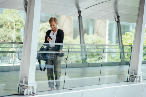 快乐的商务女性在办公室阳台上使用手机图片下载