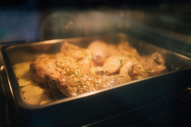 腌鸡腿、鸡胸、鸡翅和烤箱里烤的土豆，透过玻璃可以看到图片下载