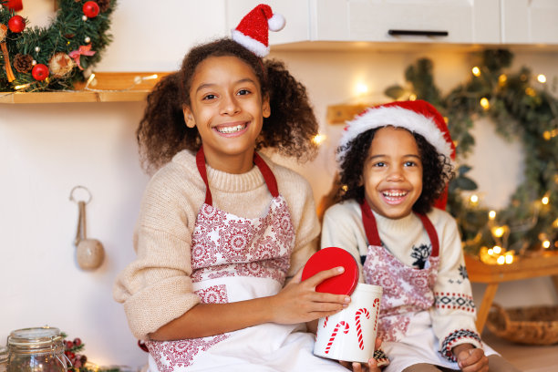 快乐的少数民族儿童在平安夜，女孩和男孩吃饼干，他们一起在家里舒适的厨房烘焙图片下载