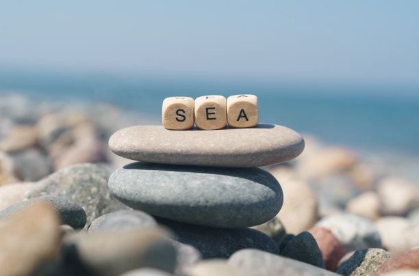 在一片石滩上，有一座金字塔形的石头，上面是刻有“海”字样的木块。图片下载