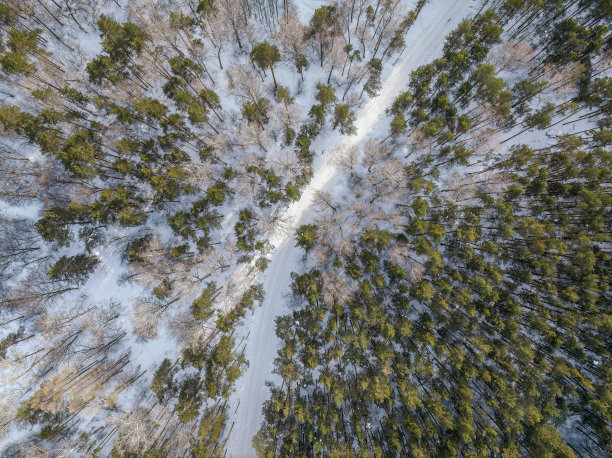 飞越冬季山脉与道路蛇形和松林。自顶向下视图。风景摄影图片下载