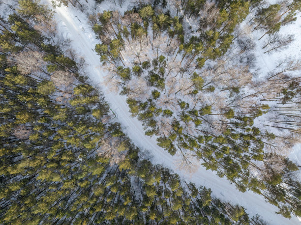 飞越冬季山脉与道路蛇形和松林。自顶向下视图。风景摄影图片下载
