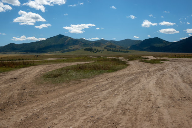 背景是开阔的田野和雄伟的山脉。乡村山水有山，蓝天有云。图片下载