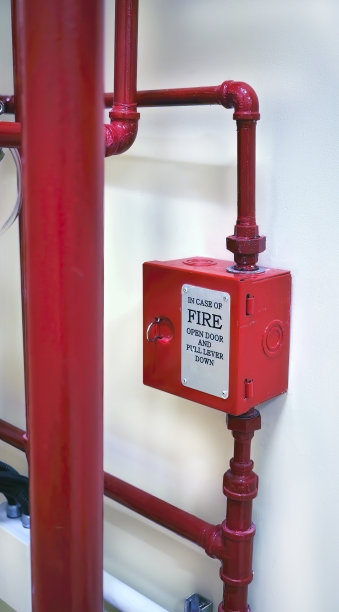 建筑内以混凝土墙为背景的消防系统红色金属箱和垂直安装红色管道图片下载
