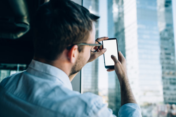 男子在办公室用智能手机拍照图片下载