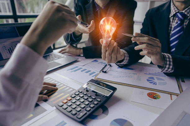商务人士举着灯泡在会议室介绍节能图片下载