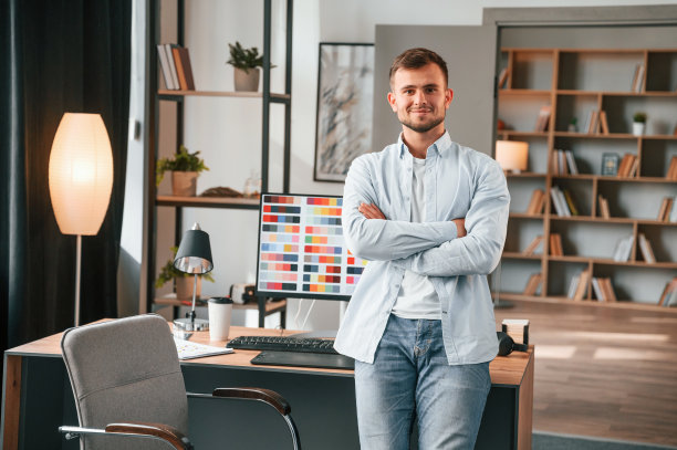站在pc面前。年轻的男设计师在现代化的办公室里图片下载