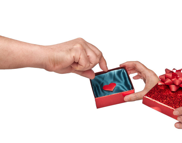 一个男人的特写，从礼盒里拿出一个红心，由一个女人拿着，孤立在白色背景和复制空间。爱的概念，激情，浪漫，浪漫，情人节，器官捐献。图片下载