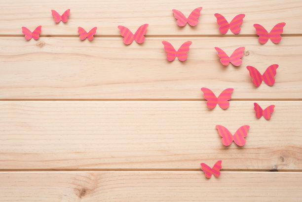 木制表面上的一些粉红色纸蝴蝶。图片下载