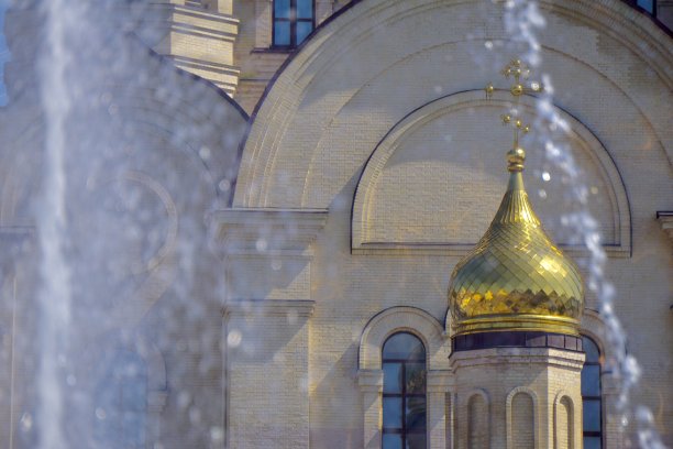 符拉迪沃斯托克广场教堂的圆顶和十字架。位于符拉迪沃斯托克广场喷泉背景上的教堂。喷泉和教堂相辅相成。水柱、十字架和基督教教堂的圆顶。图片下载