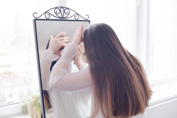 那个女孩对着镜子画画。图片下载