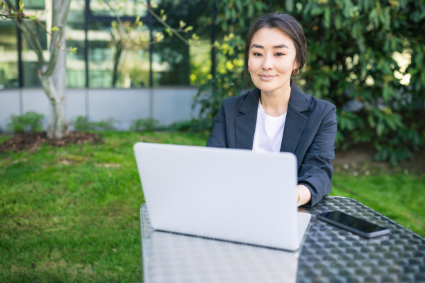 亚洲自信的商业妇女工作与笔记本电脑户外，微笑图片下载