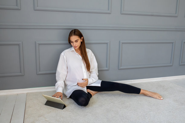 长发可爱的孕妇坐在地板上，拿着笔记本电脑图片下载