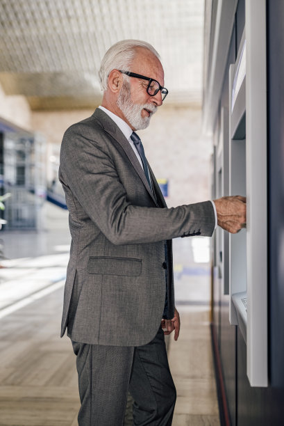 侧面的老年人专业人士使用自动取款机提现。图片下载