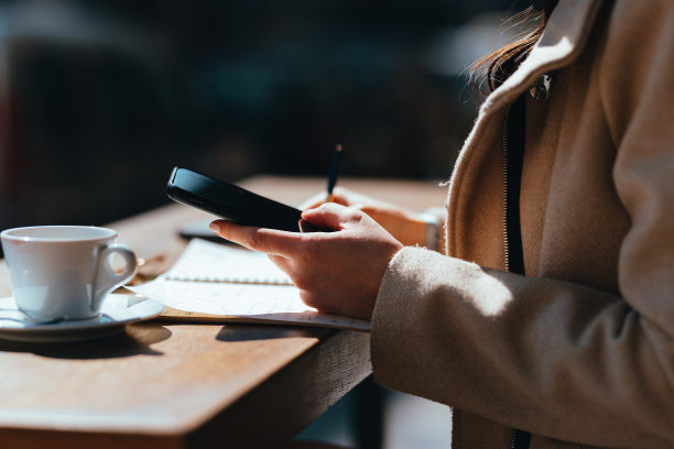 匿名女子坐在咖啡店里拿着智能手机打字(复印空间)图片下载