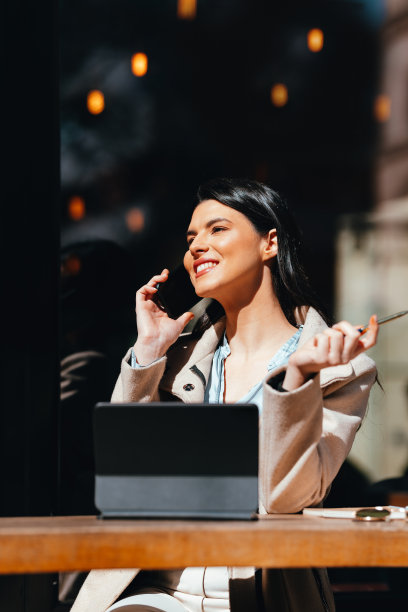 Portrait of a Beautiful Woman Having a Business Call in a Café on a Sunny Day图片下载