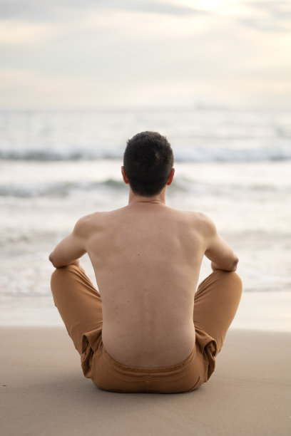 年轻的成年男子在大海前冥想，在一个平静的心灵，宁静和灵性的时刻。禅宗概念，幸福和正念。图片下载