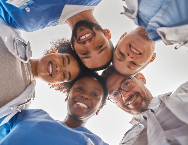 团队，多元化和医生在圈下，团队合作，医院员工的支持和帮助。一群医务人员挤在一起低头看。医护人员的队友们图片下载