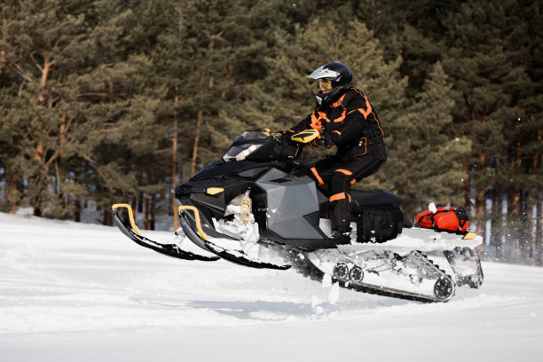 在深粉雪堆中，摩托雪橇骑手飞驰而过。图片下载