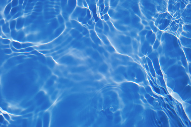 离焦模糊透明蓝色颜色清晰平静的水面纹理与飞溅和气泡。潮流抽象的自然背景。水波在阳光下复制空间。蓝色水彩闪光图片下载