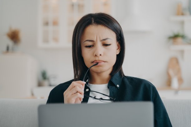困惑的女商人皱着眉头在家里的笔记本电脑上工作，解决问题，看着电脑屏幕图片下载