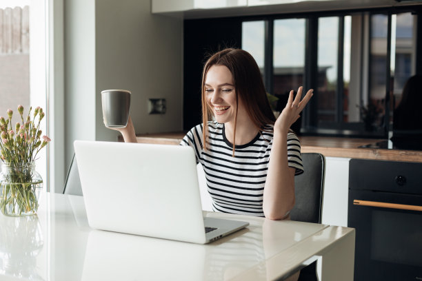 年轻的笑和开朗的女性使用白色笔记本电脑和喝咖啡。视频电话，网络研讨会，会议，远程工作图片下载