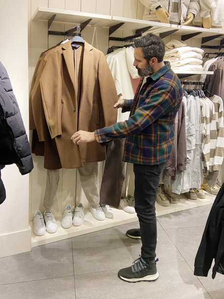 一个男人在服装店挑选衣服。男子在服装店购物图片下载