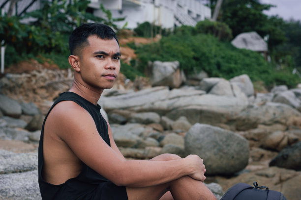 严肃的菲律宾男人坐在岩石上图片下载