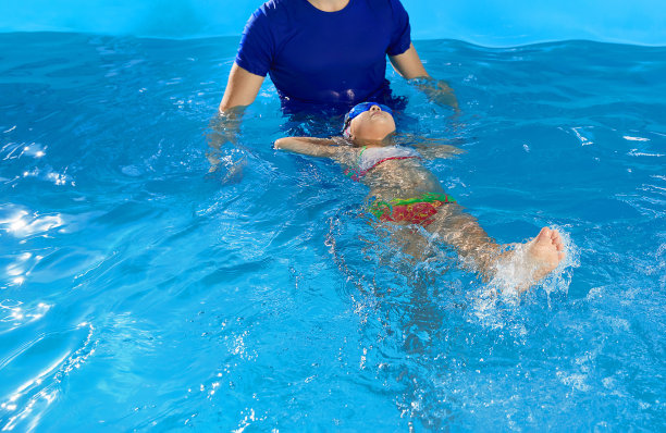 教练在室内泳池教学前班女孩如何仰卧游泳图片下载