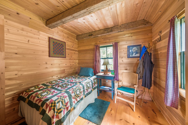 小木屋卧室，天花板上有木梁，蓝色床头柜和一把椅子图片下载