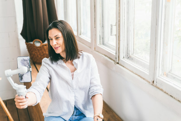 美丽的黑发持有稳定与电话在她的手中和广播视频图片下载