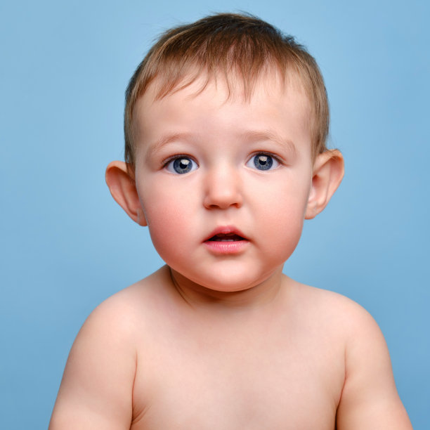 惊讶的蹒跚学步的男婴，工作室蓝色背景。一个可爱的悲伤的孩子的肖像，特写。一岁零两个月的孩子图片下载