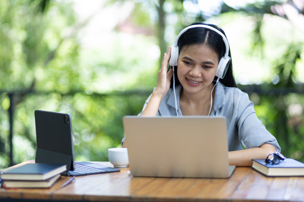 户外商务女士穿着休闲服装，正在笔记本电脑和现代化设备上工作，在自然舒适的环境中，举行网络会议。图片下载