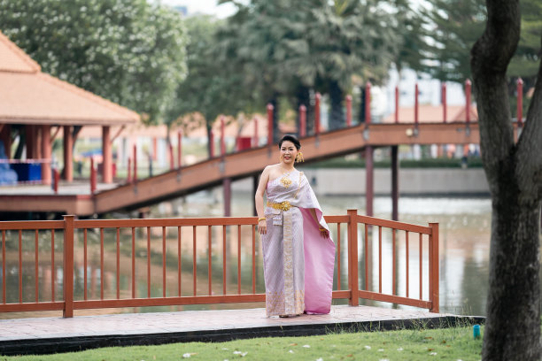 图为，身穿泰国传统服饰的女子站在木桥上拍摄人像照片。图片下载