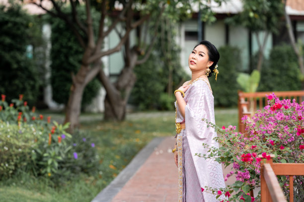 图为，身穿泰国传统服饰的女子站在木桥上拍摄人像照片。图片下载