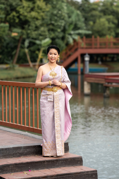 图为，身穿泰国传统服饰的女子站在木桥上拍摄人像照片。图片下载